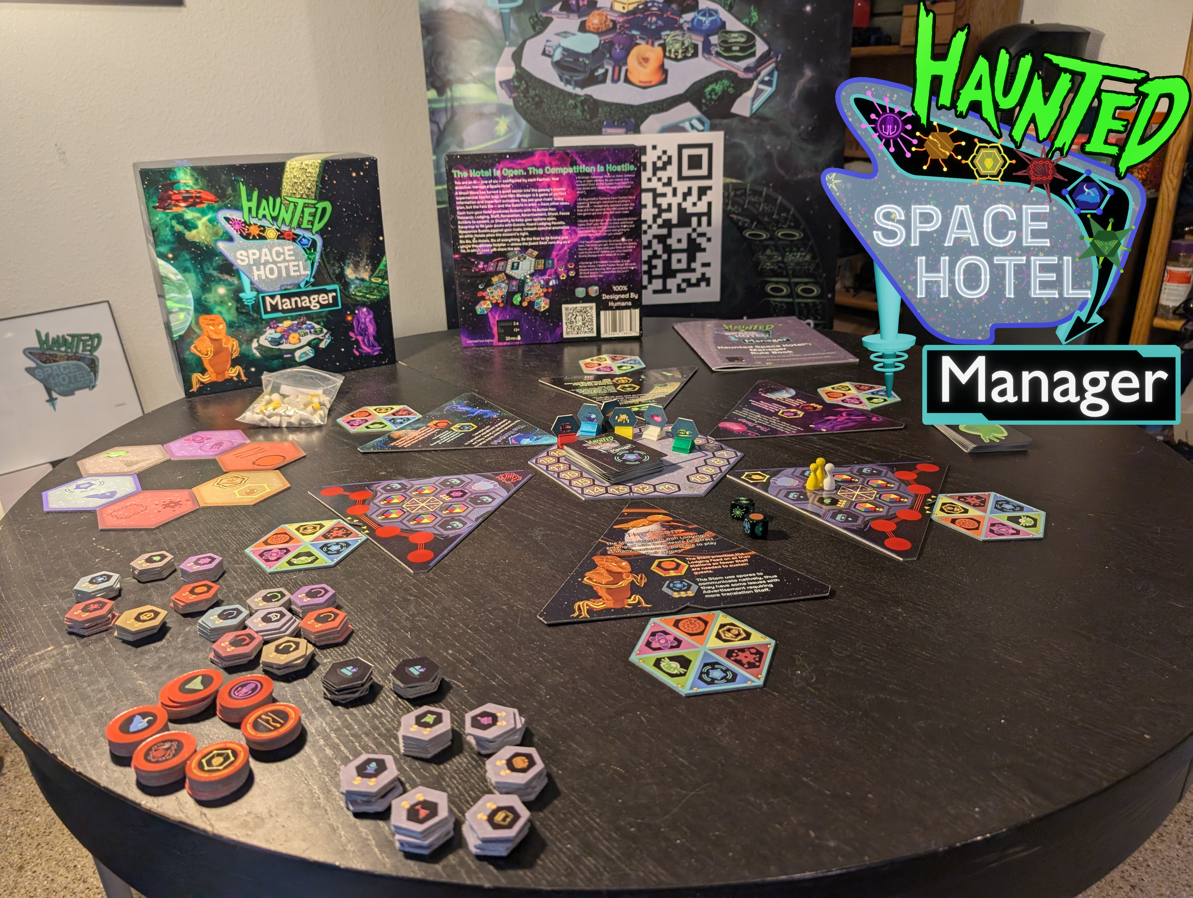 Haunted Space Hotel: Manager first-edition proof copy on a table — box, components, hex player boards, faction tokens, and Action Hex tiles laid out.